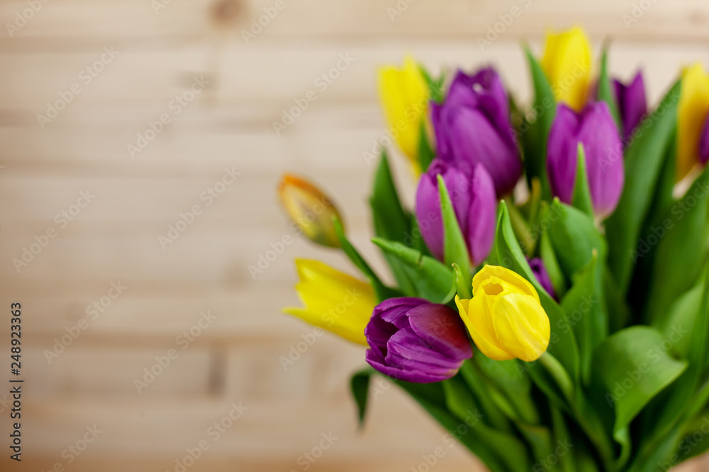 A bouquet of tulips on a light wooden background with a place for text
