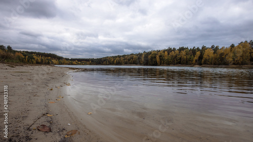 Great lake with sandy beach in autumn weather.