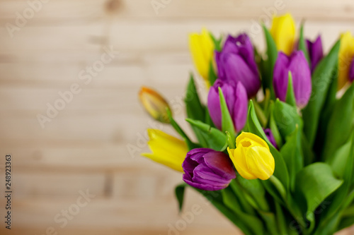 Fototapeta Naklejka Na Ścianę i Meble -  A bouquet of tulips on a light wooden background with a place for text