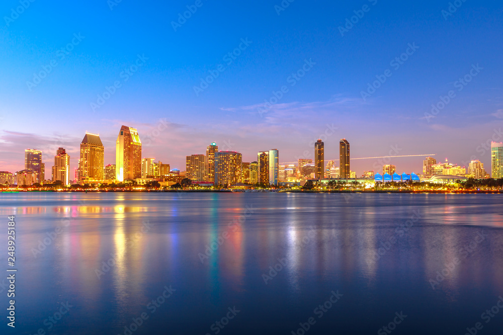 Obraz premium Panoramiczny krajobraz San Diego linia horyzontu z iluminującymi drapaczami chmur odbija w San Diego zatoce przy zmierzchem. Dzielnice Waterfront Marina skyline i miejskiego centrum miasta o zachodzie słońca światła.