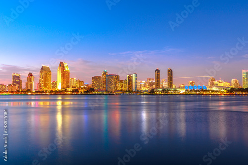 Panoramic landscape of San Diego skyline with illuminated skyscrapers reflecting in San Diego Bay at twilight. Districts of Waterfront Marina skyline and urban downtown cityscape at sunset light.