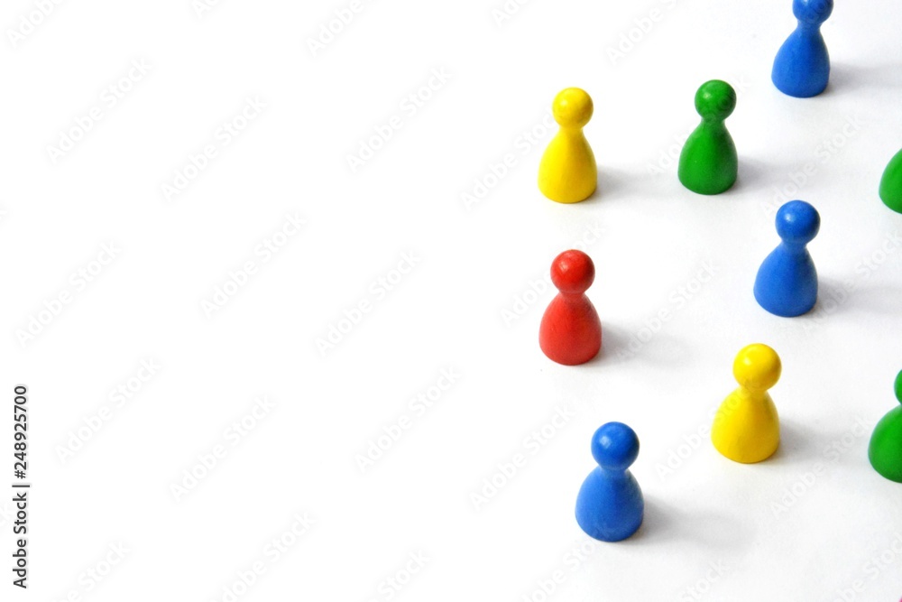 Game figures from a board game in different colors stand on a white background and throw all the shadows in one direction - concept with different figures on white background