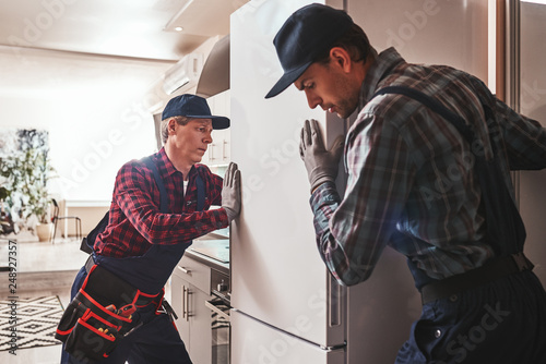 Easy to solve. Young men mechanics checking refrigerator