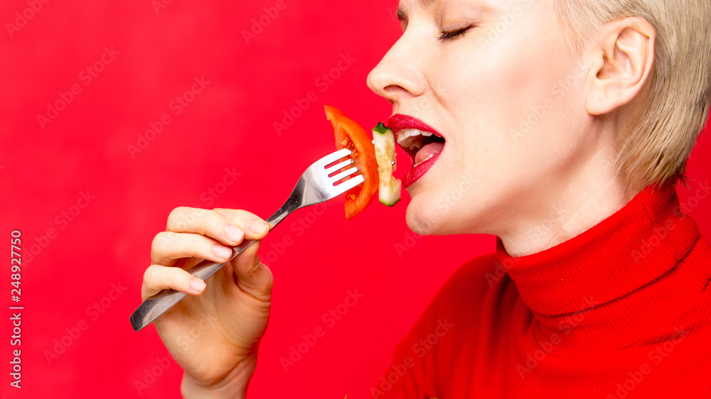Beautiful caucasian woman eating salad over red background Beautiful caucasian woman eating salad over red background