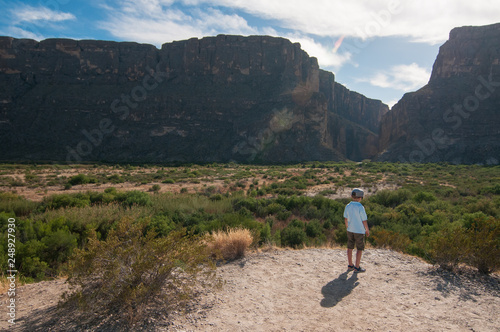 a small boy standing in front of mountain wall in a Big Bend National Park, Texas