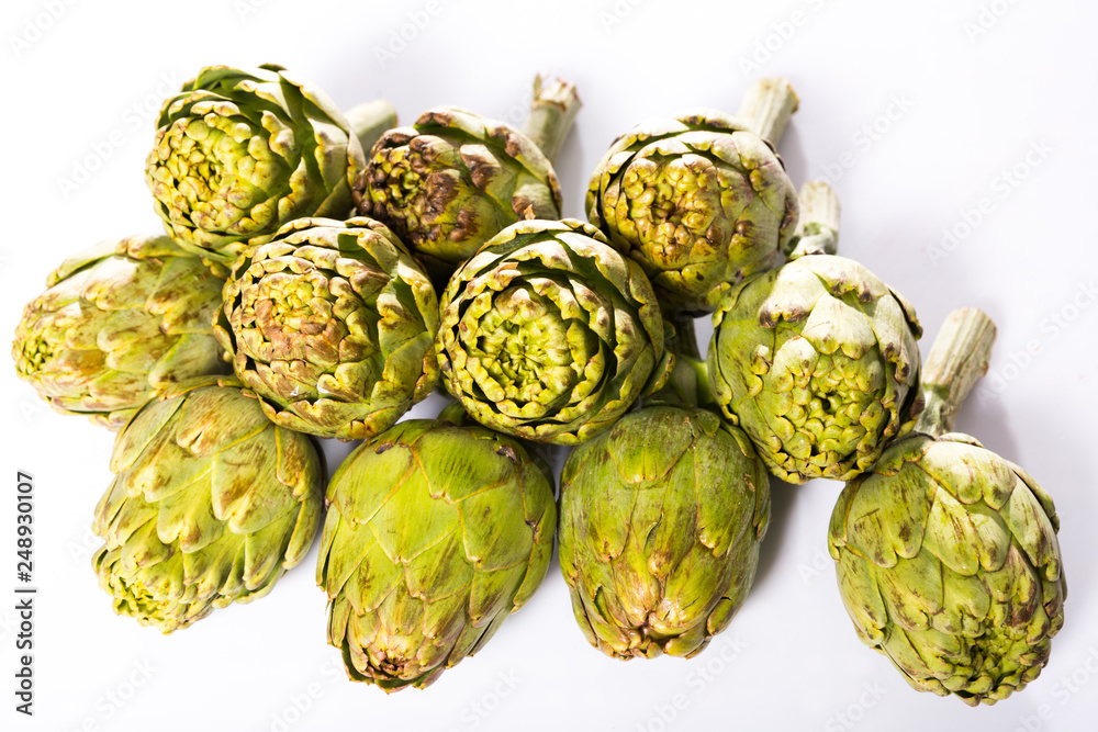 Obraz premium Uncooked green artichokes on a white surface