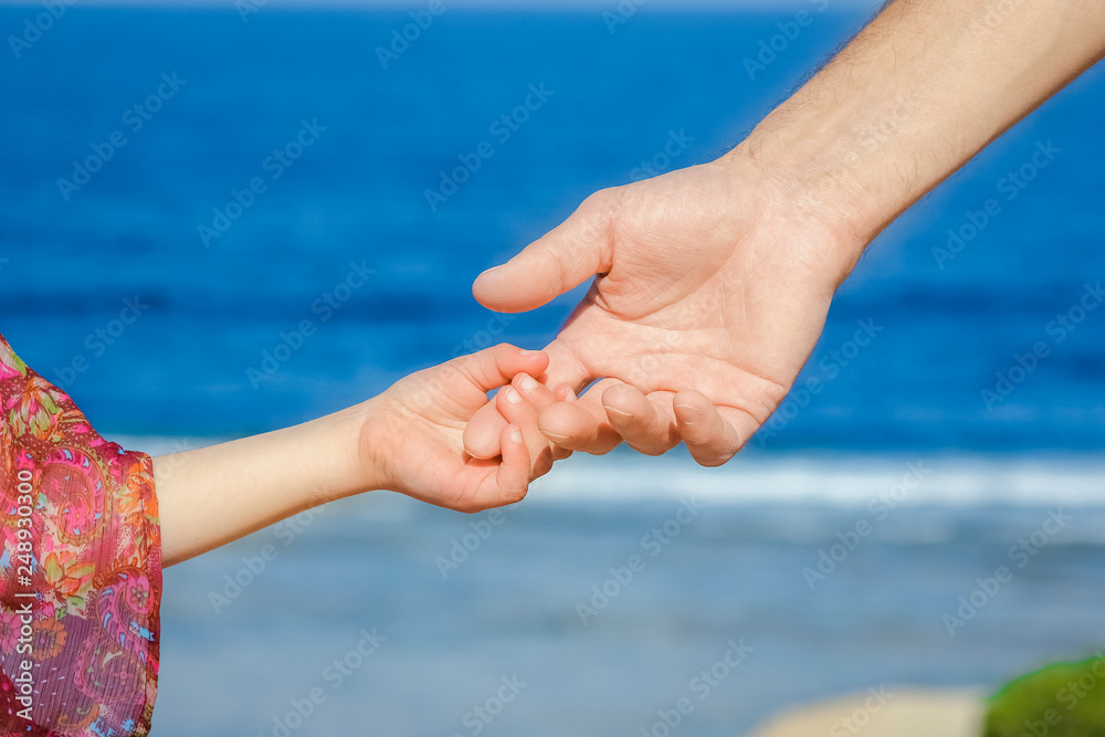 Beautiful hands of parent and child on sea background Beautiful hands of parent and child on sea background