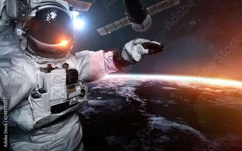 Fototapeta Naklejka Na Ścianę i Meble -  Astronaut at spacewalk against international space station. Science fiction art. Elements of this image furnished by NASA