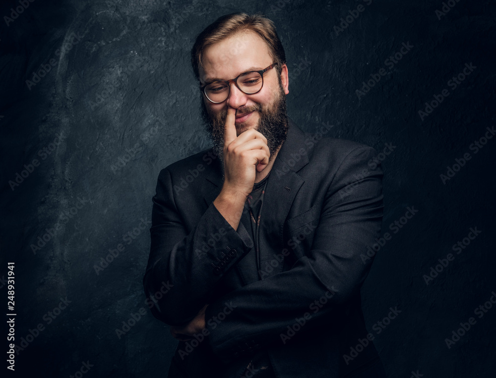 Bearded hipster picks his nose and smiles on a black background in the studio Bearded hipster picks his nose and smiles on a black background in the studio