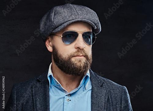 Close-up portrait of a successful stylish man in sunglasses wearing a beret and jacket © Fxquadro