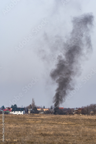 Black Smoke Rising to the Sky from a Field on a Sunny Winter Day