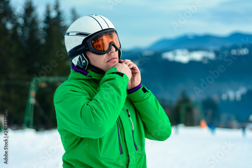 A man skier wearing a helmet and sunglasses before training for safety