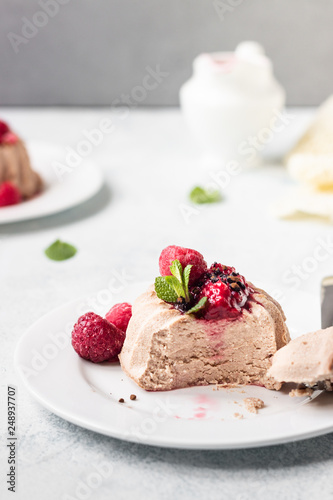 Two mini chocolate cheesecake with raspberry sauce and mint. No crust cheesecake. Diet dessert. Light grey stone concrete background. Copy space.
