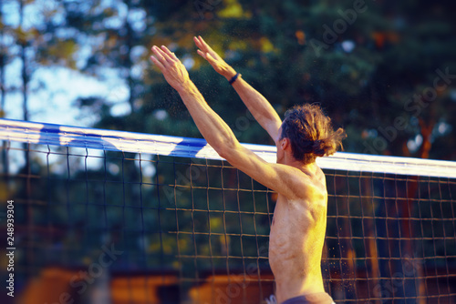 the guy is playing volleyball jumping near the volleyball net