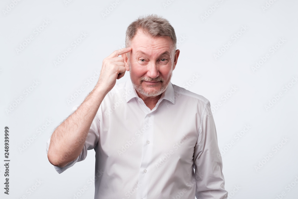 Mature european man pointing on temple with fingers
