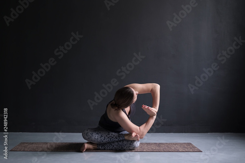 Womanl working out, doing yoga exercise on floor twisted agnistambhasana photo