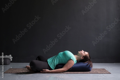 Foto Woman practicing yoga concept, lying in Reclined Butterfly exercise