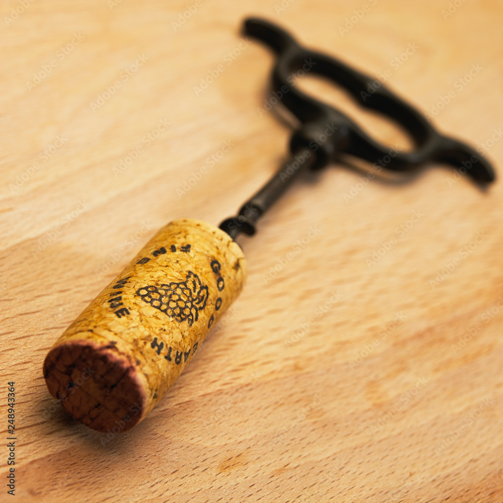 OLD ANTIQUE CORKSCREW AND CORK ON WOODEN TABLE