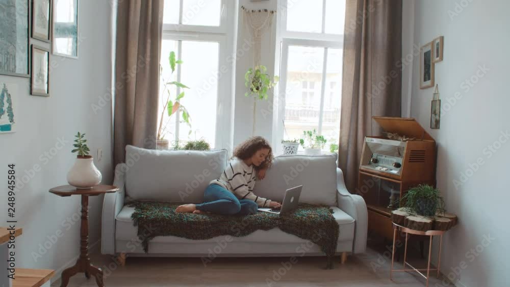Pretty woman relaxing on sofa using her laptop at home in the living room. Pretty woman relaxing on sofa using her laptop at home in the living room.