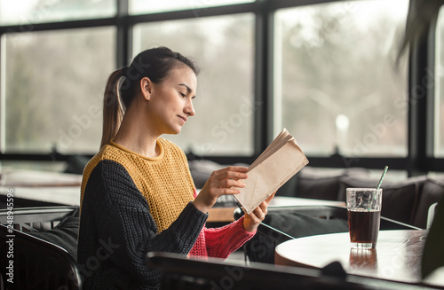Young beautiful woman in orange sweater reading interesting book in cafe Free Download Young beautiful woman in orange sweater reading interesting book in cafe - GFXLoad