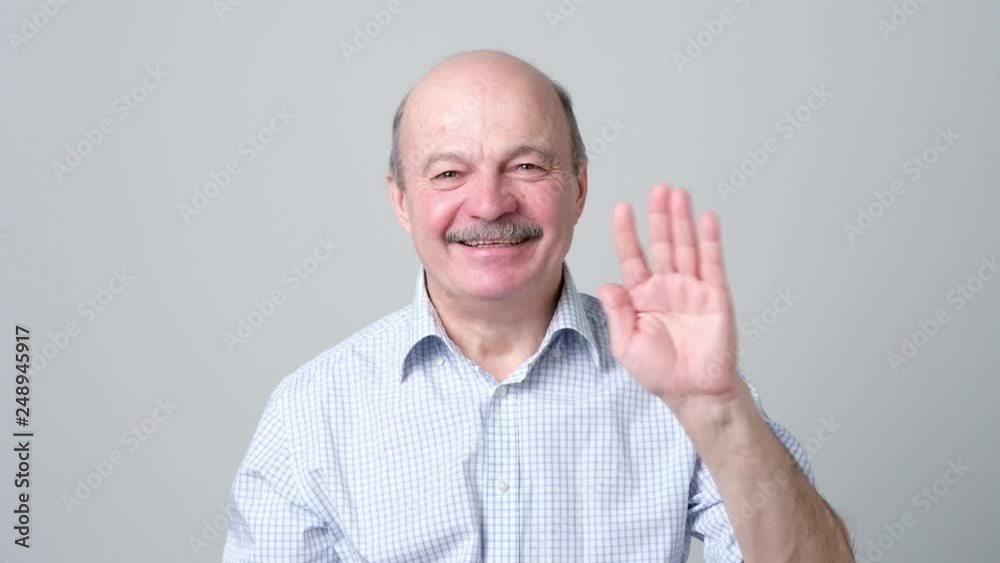Attractive european man waiving hand in hello gesture while smiling cheerfully. Attractive european man waiving hand in hello gesture while smiling cheerfully.