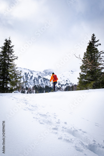 Man with orange jacket snowshoeing in Hohentauern on cloudy winterday