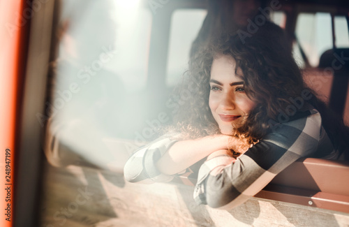 A young girl looking out of a car on a roadtrip through countryside.