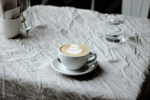 Processed witon a natural linen tablecloth a white cup of coffee with whipped creamh VSCO with m5 preset photo