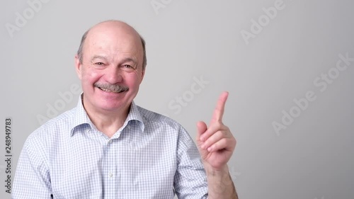 Senior man in blue shirt pointing with index finger to important information
