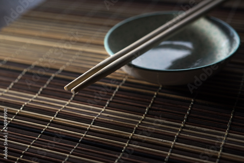 Ceramic bowl with chopsticks on bamboo background