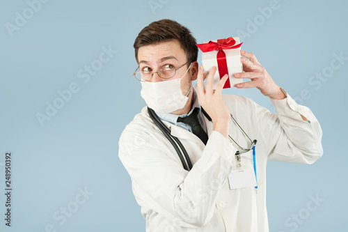 doctor student with a gift in his hands on an isolated blue background.concept medicine and health, holidays and gifts