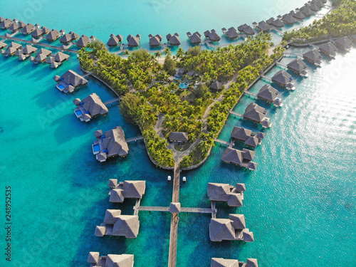 Aerial view of overwater bungalow villas with thatched roofs in the Bora Bora lagoon in French Polynesia