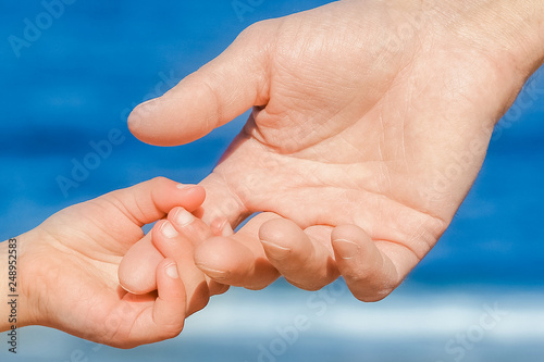 Beautiful hands of parent and child on sea background © Kostia