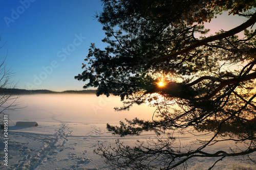 Winter sunset by the snowy and icy lake in Sweden.