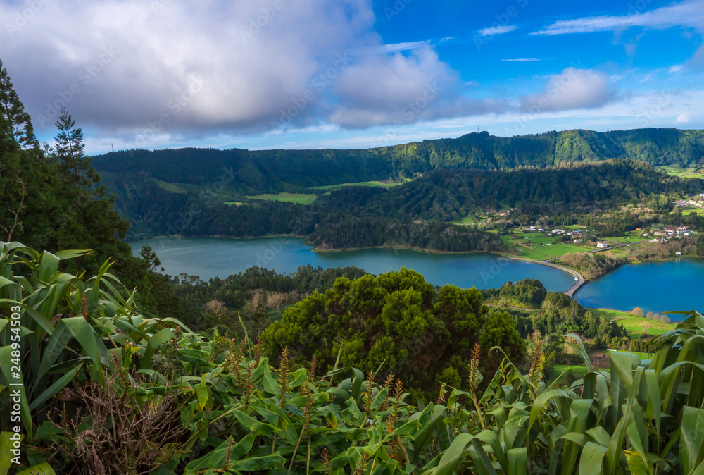 Aerial view of landscape with green and blue crater lakes of Lagoa Azul and Lagoa Verde and Sete Cidades village in the crater of dormant volcanoes, on Sao Miguel island, Azores, Portugal.