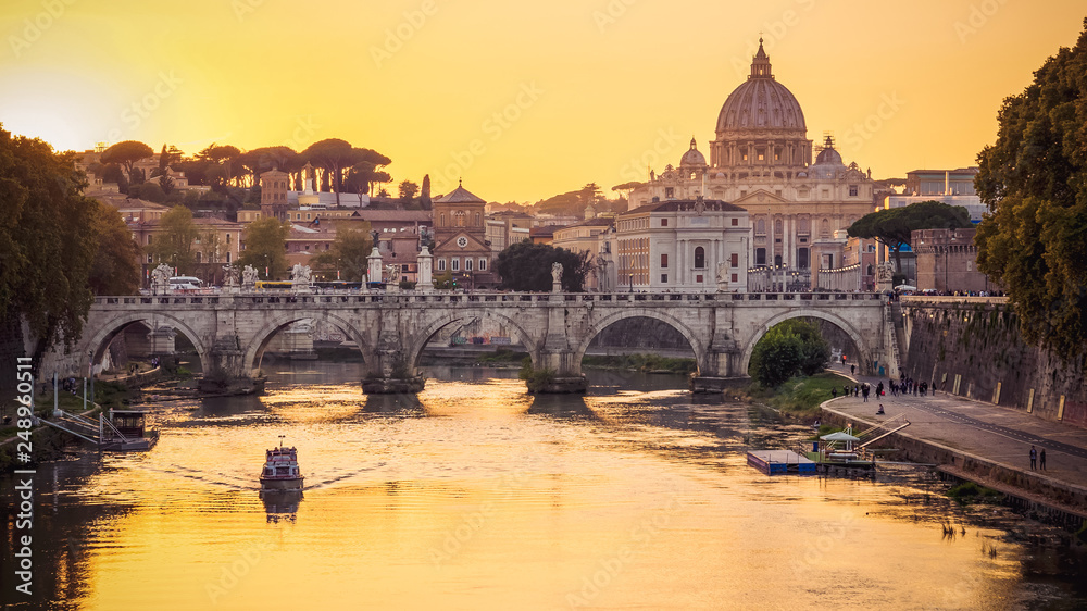 The dome of Saint Peters Basilica and Vatican City at sunset. Sant'Angelo Bridge over the Tiber River. Rome, Italy