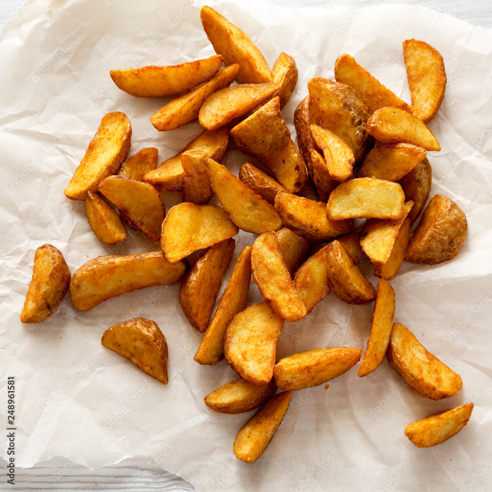 Fried potato wedges on baking sheet. From above, overhead, top view. Close-up. Fried potato wedges on baking sheet. From above, overhead, top view. Close-up.