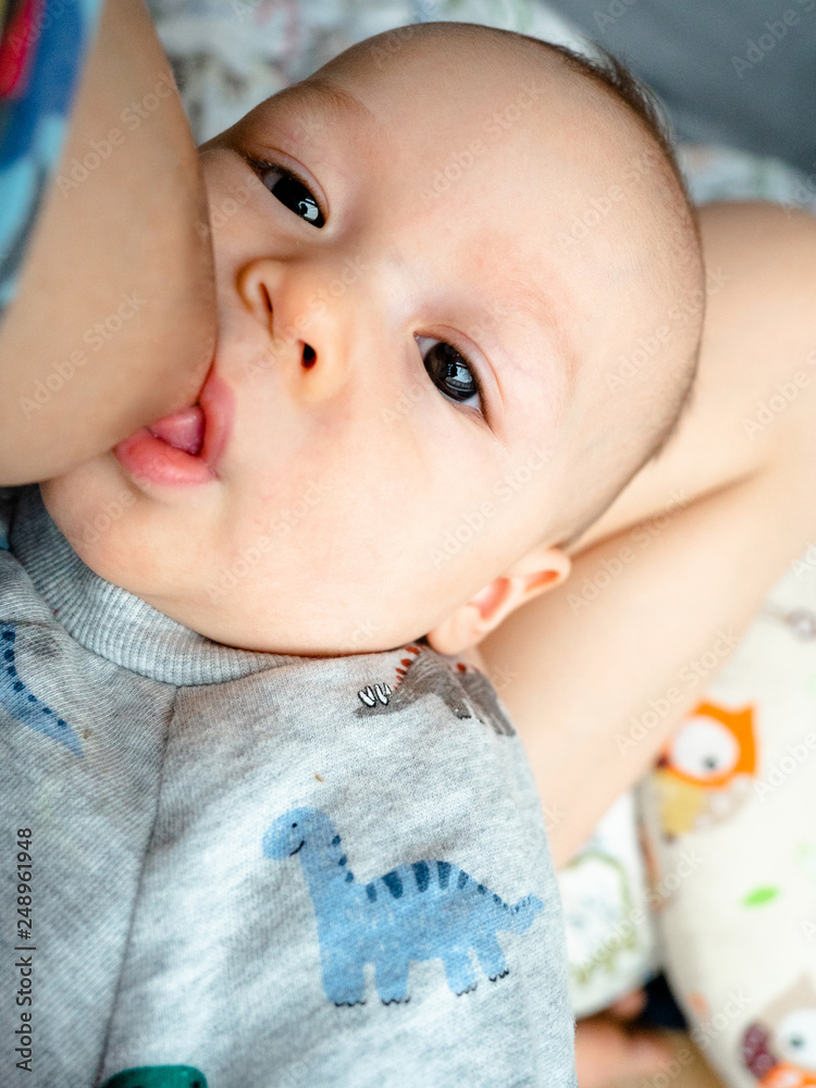 close up of mother breast feeding her newborn baby boy at home, Happy baby  Cute 4 months old mixed half race Asian Caucasian, healthy child baby boy.  Half Thai half Polish. Stock