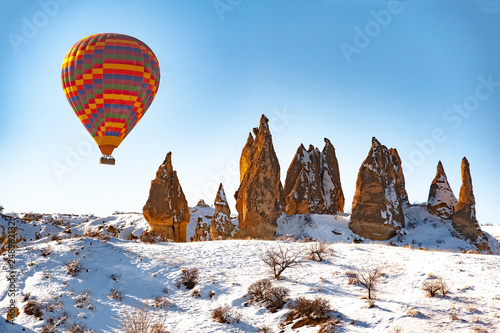 colorful balloon over the extraordinary rocks formations rock hills on snowy winter of Cappadocia, Nevsehir,