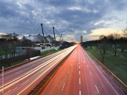 Light trails of cars driving/commuting past modern architecture in a city - Munich, Germany