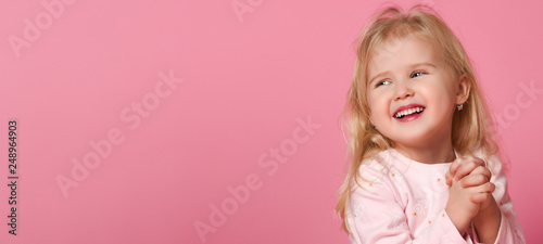 Little cute girl child blonde in a pink suit is shy 