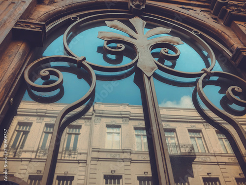 Reflection of a building on the street in a glass wooden door with an iron decorative ornament. Old Tbilisi architecture photo