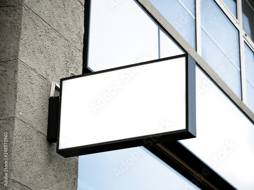 Black frame signboard side view of empty white mock-up modern with city brick wall background exterior display. Signboard side view of empty white mock up, squared, box, signage.