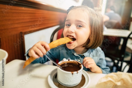 Kid eating churros and chocolate