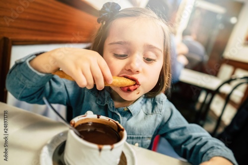 Kid eating churros and chocolate