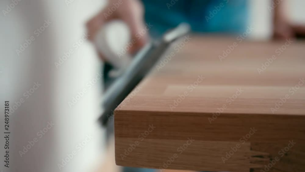 Close Up Shot of Carpenter Man Sanding and Rubbing Wooden Desk with Sandpaper on Grip, Making Oak Wooden Table at Home Close Up Shot of Carpenter Man Sanding and Rubbing Wooden Desk with Sandpaper on Grip, Making Oak Wooden Table at Home