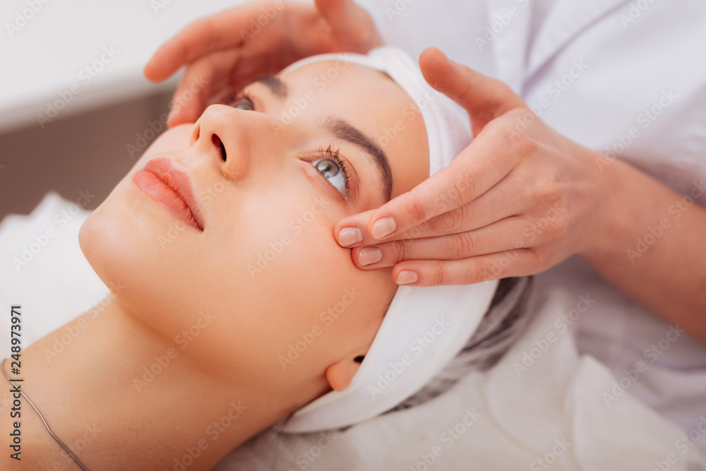 Face of a pleasant young woman during facial massage