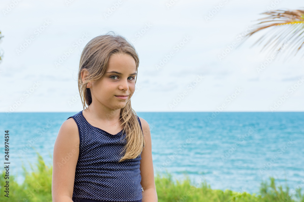 Criança modelo sentada em frente ao mar azul Criança modelo sentada em frente ao mar azul