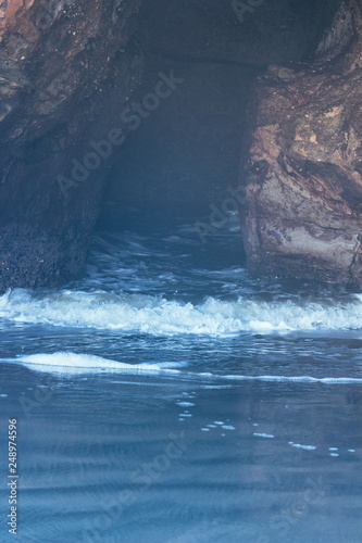 Natural formed cave where the ocean comes through the rock at Wharariki Beach. Wharariki Beach is west of Cape Farewell  the northernmost point of the South Island of New Zealand.