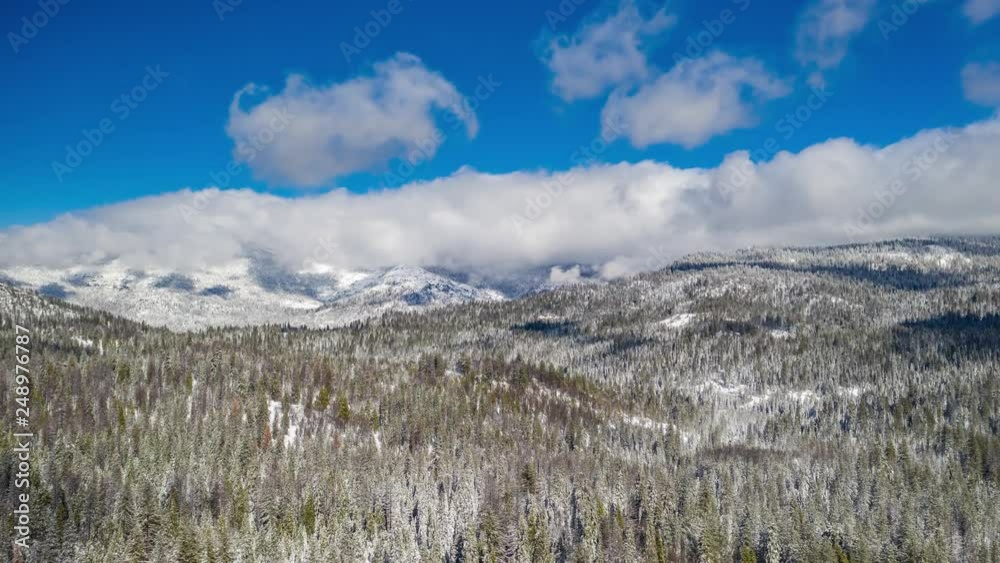 Aerial hyper lapse moving to the left in snowy landscape with mountains. Fast moving clouds, grand epic view.